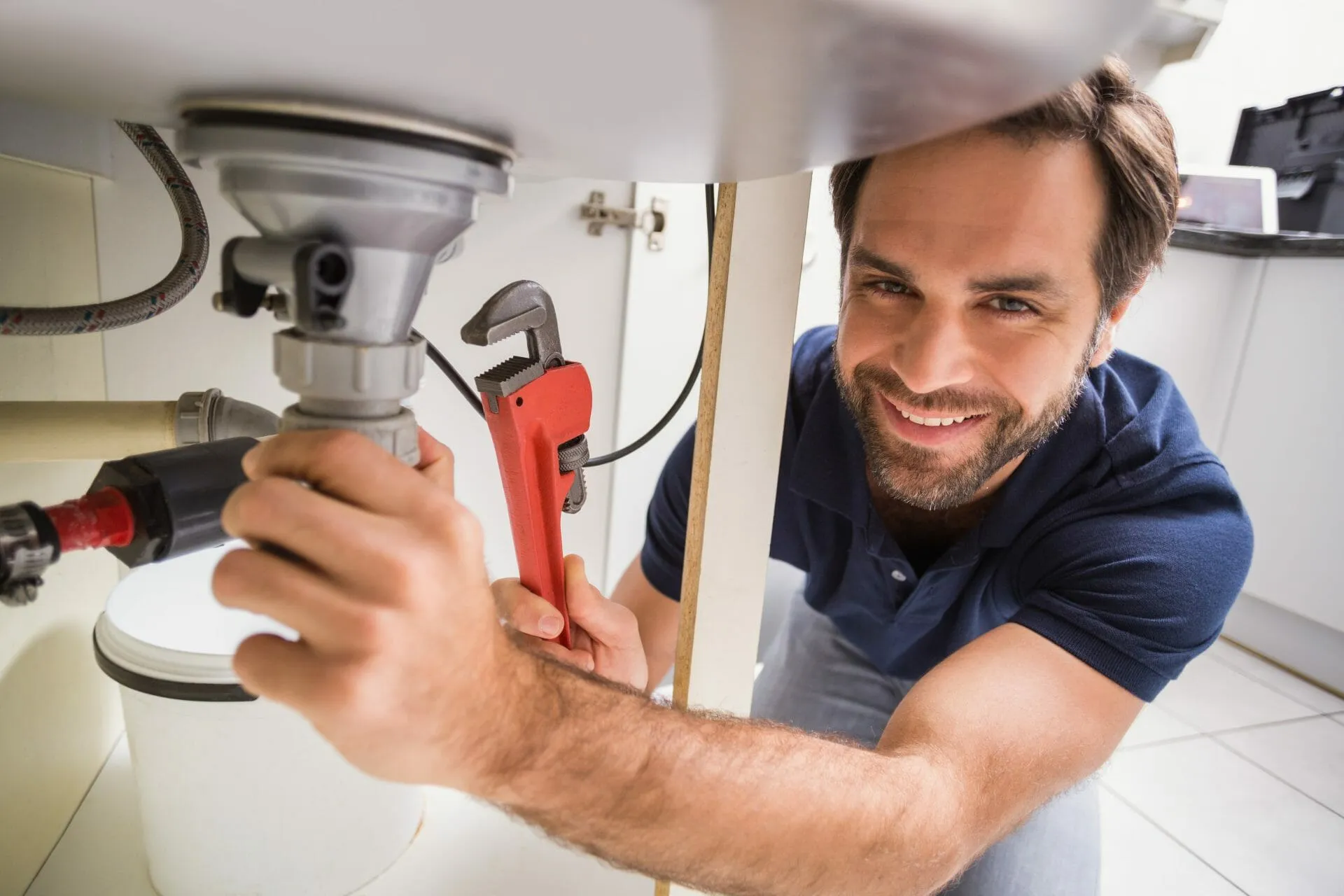 smiling plumber fixing a sink