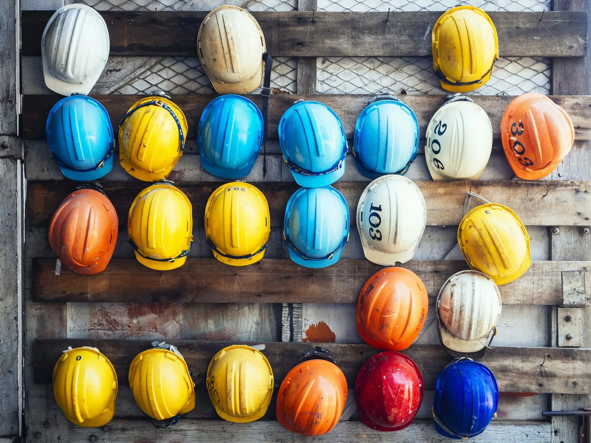 builders coloured hard hats hanging on wall